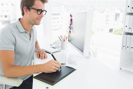 editor designer - Side view of a casual male photo editor using graphics tablet in a bright office Stock Photo - Budget Royalty-Free & Subscription, Code: 400-07273672