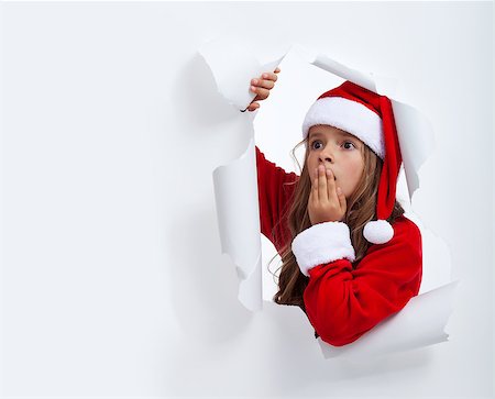 Surprised Santa girl looking through hole in paper - with copy space Stock Photo - Budget Royalty-Free & Subscription, Code: 400-07297822