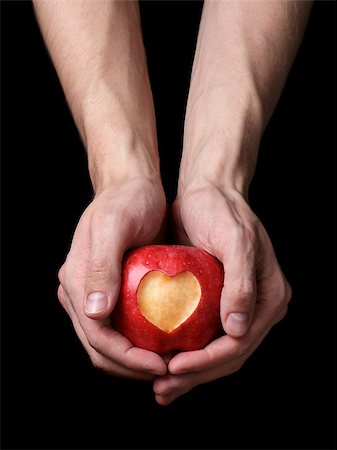adult man hands holding apple with carved heart, isolated on black Stock Photo - Budget Royalty-Free & Subscription, Code: 400-07298814