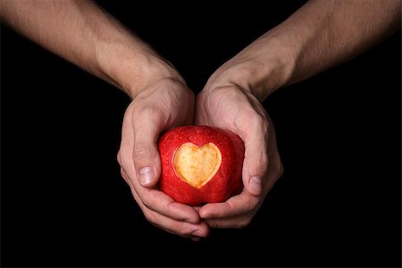 adult man hands holding apple with carved heart, isolated on black Stock Photo - Budget Royalty-Free & Subscription, Code: 400-07298815