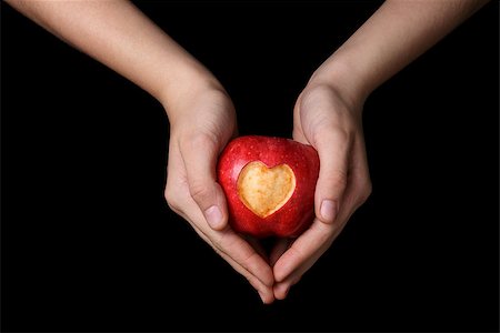 female teen hands holding apple with carved heart, isolated on black Stock Photo - Budget Royalty-Free & Subscription, Code: 400-07298816
