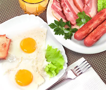 simsearch:400-04414187,k - Breakfast - fried eggs, salad, bacon, sausages, bread and glass of orange juice. Photographie de stock - Aubaine LD & Abonnement, Code: 400-07304561