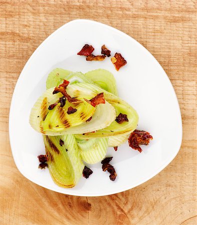 simsearch:400-07625359,k - Tasty Roasted Leek with Fried Tomatoes and Paprika on White Plate closeup on Wooden background. Top View Photographie de stock - Aubaine LD & Abonnement, Code: 400-07304674