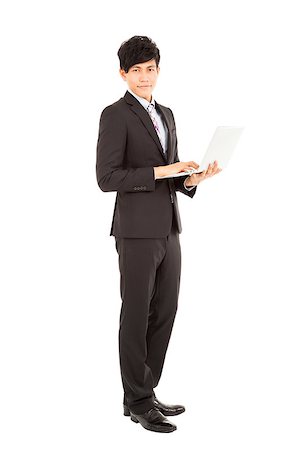 simsearch:400-07514126,k - Full length of  young businessman standing with laptop Fotografie stock - Microstock e Abbonamento, Codice: 400-07305582