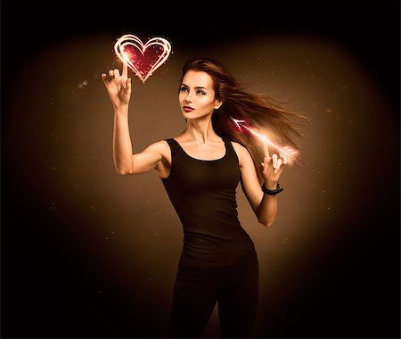 person pointing at heart - Sexy Woman Aiming to the Glowing Heart with an Arrow on Dark Background. Fantasy Cupid Concept for Valentine's Day. Stock Photo - Budget Royalty-Free & Subscription, Code: 400-07308093