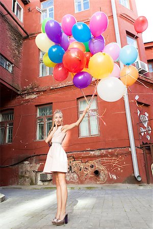 elio - beautiful surprised girl in pink dress holding a bunch of balloons in front of old wall Fotografie stock - Microstock e Abbonamento, Codice: 400-07300815