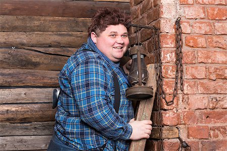 Happy overweight young man standing against a brick wall at the top of a stepladder laughing Stock Photo - Budget Royalty-Free & Subscription, Code: 400-07301612