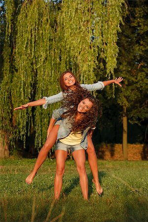 simsearch:400-05372366,k - teenage girl giving her girlfriend piggyback ride in park Photographie de stock - Aubaine LD & Abonnement, Code: 400-07303711