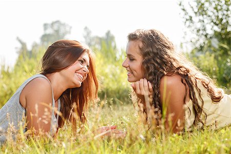 two girlfriends lying down on grass talking Stock Photo - Budget Royalty-Free & Subscription, Code: 400-07303766