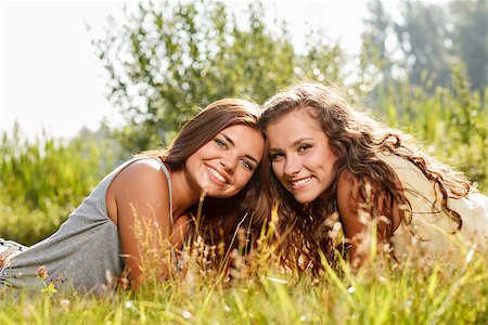 two girlfriends wearing T-shirts lying down on grass smiling looking at camera Stock Photo - Budget Royalty-Free & Subscription, Code: 400-07303767