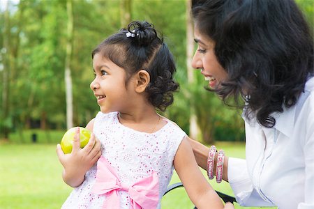 Happy Indian family. Asian girl holding an green apple at outdoor with mother. Stock Photo - Budget Royalty-Free & Subscription, Code: 400-07318228