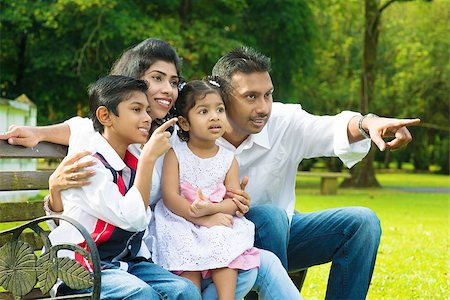 Happy Indian family at outdoor park. Candid portrait of parents and children having fun at garden park. Fingers pointing away. Stock Photo - Budget Royalty-Free & Subscription, Code: 400-07318222