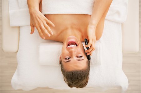 Happy young woman laying on massage table and talking cell phone Photographie de stock - Aubaine LD & Abonnement, Code: 400-07319450