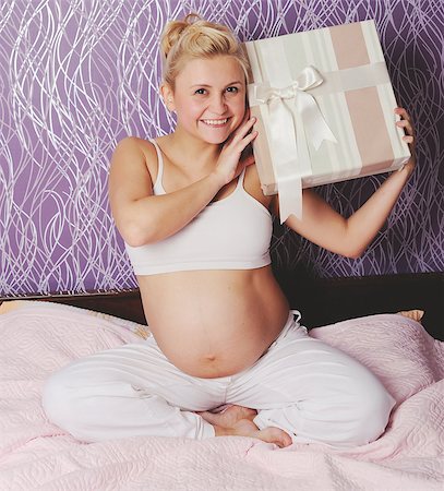 young pregnant woman sitting on bed at home, holding present Photographie de stock - Aubaine LD & Abonnement, Code: 400-07312085