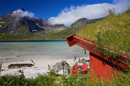 Traditional fishing hut on the beach by fjord with mountain peaks high in the clouds on Lofoten islands in Norway Photographie de stock - Aubaine LD & Abonnement, Code: 400-07313847