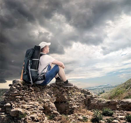 Tourist sitting on the rocks under cloudy sky Stock Photo - Budget Royalty-Free & Subscription, Code: 400-07324694