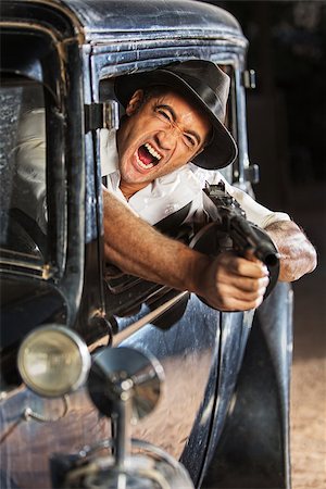 simsearch:400-07313982,k - Yelling man firing submachine gun from vintage 1920s car Stockbilder - Microstock & Abonnement, Bildnummer: 400-07324714