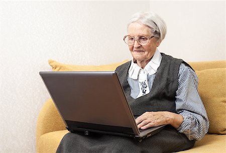 Senior woman using laptop computer while sitting on sofa Stock Photo - Budget Royalty-Free & Subscription, Code: 400-07326186