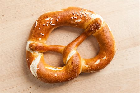 photo of people eating pretzels - An image of a delicious bavarian pretzel on a wooden background Stock Photo - Budget Royalty-Free & Subscription, Code: 400-07327968