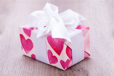 simsearch:400-06873734,k - Pretty Valentines gift with hearts on the giftwrap on a big white ornamental bow on top, closeup high angle view of a gift for a loved one or sweetheart Stock Photo - Budget Royalty-Free & Subscription, Code: 400-07328450