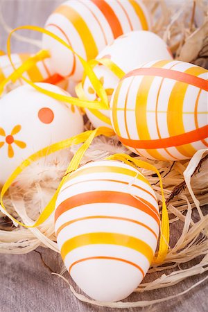 paille (décoration) - Close-up of decorative traditional Easter eggs, painted with yellow and orange horizontal stripes, with ribbons and straw, on a rustic wooden table Photographie de stock - Aubaine LD & Abonnement, Code: 400-07328496