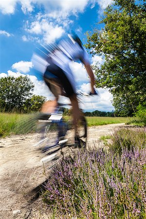simsearch:400-04499588,k - Cyclist in blurred motion riding on a rural road through green spring meadow Fotografie stock - Microstock e Abbonamento, Codice: 400-07329114