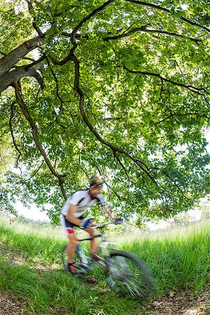 simsearch:400-04499588,k - Cyclist in blurred motion riding a bike in a forest; summer season, blur motion effect. Fotografie stock - Microstock e Abbonamento, Codice: 400-07329112