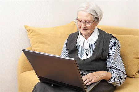 Senior woman using laptop computer while sitting on sofa Stock Photo - Budget Royalty-Free & Subscription, Code: 400-07329320