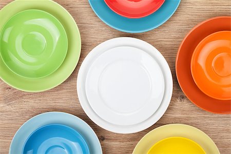 Colorful plates and saucers over wooden table background. View from above Stock Photo - Budget Royalty-Free & Subscription, Code: 400-07320184