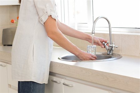 pictures of water glass and faucet - Side view mid section of a woman washing glass at washbasin in the kitchen at home Stock Photo - Budget Royalty-Free & Subscription, Code: 400-07334106