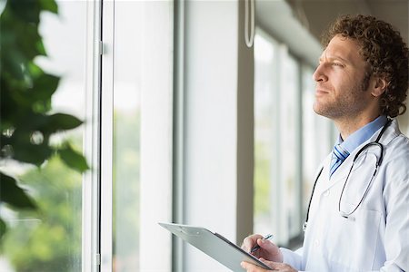 simsearch:400-07334526,k - Thoughtful male doctor with clipboard in hospital Stock Photo - Budget Royalty-Free & Subscription, Code: 400-07334522