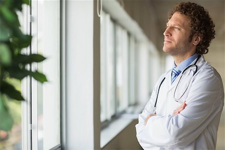 simsearch:400-07334526,k - Thoughtful male doctor standing arms crossed in hospital Stock Photo - Budget Royalty-Free & Subscription, Code: 400-07334523