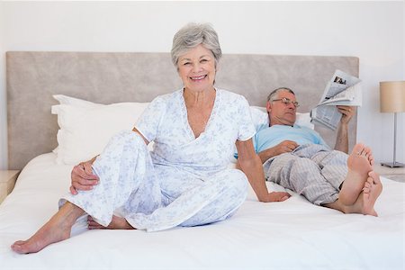 simsearch:400-07334704,k - Portrait of happy senior woman sitting with man reading newspaper in background on bed Stock Photo - Budget Royalty-Free & Subscription, Code: 400-07334654