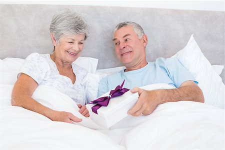 simsearch:400-07334704,k - Senior man giving gift box to wife while relaxing in bed at home Stock Photo - Budget Royalty-Free & Subscription, Code: 400-07334659
