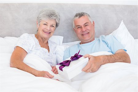 simsearch:400-07334704,k - Portrait of senior man giving gift to wife while relaxing in bed at home Stock Photo - Budget Royalty-Free & Subscription, Code: 400-07334660
