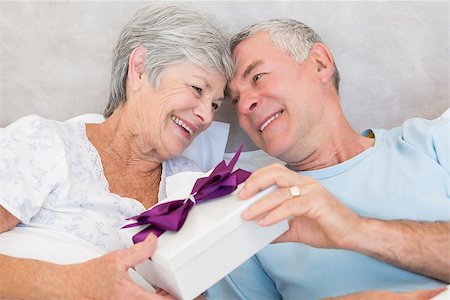 simsearch:400-07334704,k - Happy senior couple exchanging gift box while relaxing in bed at home Stock Photo - Budget Royalty-Free & Subscription, Code: 400-07334662