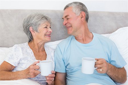 simsearch:400-07334704,k - Senior couple with coffee cups while looking at each other in bed at home Stock Photo - Budget Royalty-Free & Subscription, Code: 400-07334685