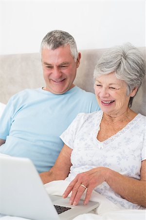 simsearch:400-07334704,k - Senior couple using laptop computer while smiling in bed at home Stock Photo - Budget Royalty-Free & Subscription, Code: 400-07334692