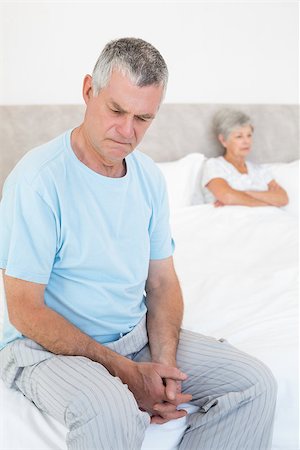 simsearch:400-07334704,k - Sad senior man sitting on bed with wife in background at home Stock Photo - Budget Royalty-Free & Subscription, Code: 400-07334706