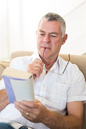 simsearch:400-04026722,k - Concentrated man reading book while sitting on sofa at home Stock Photo - Budget Royalty-Free & Subscription, Code: 400-07334714