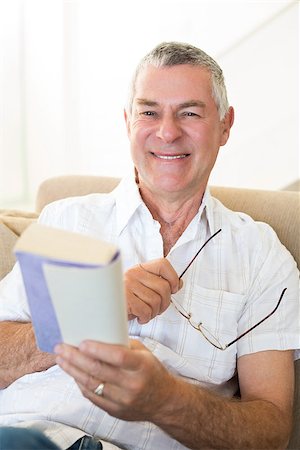 simsearch:400-04026722,k - Portrait of smiling senior man holding book and glasses at home Stock Photo - Budget Royalty-Free & Subscription, Code: 400-07334715