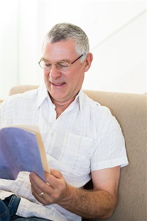 simsearch:400-04026722,k - Senior man reading book while sitting on sofa at home Stock Photo - Budget Royalty-Free & Subscription, Code: 400-07334712