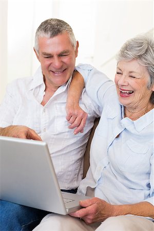 simsearch:400-07334704,k - Happy senior couple looking at laptop while sitting on sofa at home Stock Photo - Budget Royalty-Free & Subscription, Code: 400-07334728
