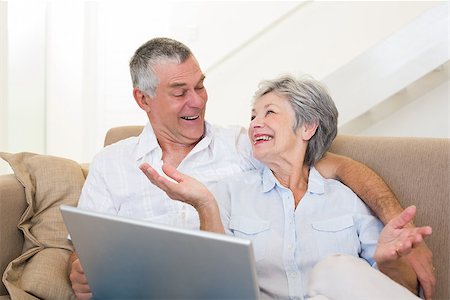 simsearch:400-07334704,k - Loving senior couple with laptop looking at each other on sofa at home Stock Photo - Budget Royalty-Free & Subscription, Code: 400-07334729