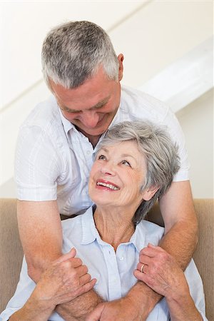 simsearch:400-04151970,k - Senior man hugging wife sitting on sofa at home Fotografie stock - Microstock e Abbonamento, Codice: 400-07334736