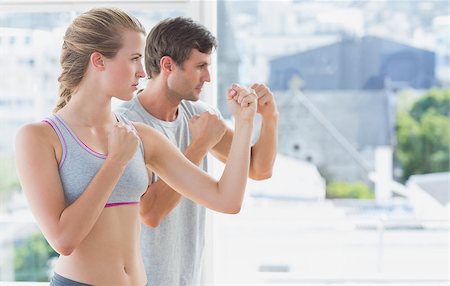 Side view of a serious young couple standing in boxing stance in fitness studio Stock Photo - Budget Royalty-Free & Subscription, Code: 400-07335203