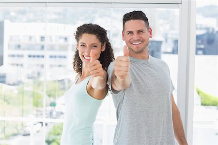 Portrait of fit couple gesturing thumbs up in bright exercise room Stock Photo - Budget Royalty-Free & Subscription, Code: 400-07335228