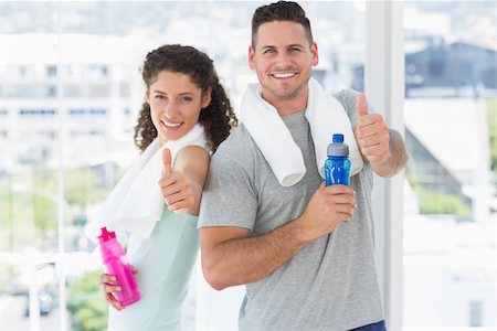 Portrait of happy couple with water bottles gesturing thumbs up at gym Stock Photo - Budget Royalty-Free & Subscription, Code: 400-07335231