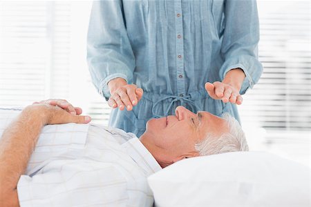 simsearch:400-07335332,k - Female therapist performing Reiki over senior man at health spa Fotografie stock - Microstock e Abbonamento, Codice: 400-07335323