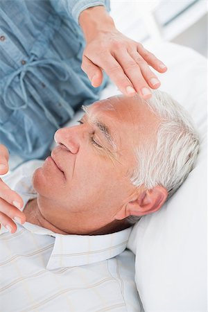 simsearch:400-07335332,k - Closeup of senior man receiving Reiki treatment by therapist at health spa Fotografie stock - Microstock e Abbonamento, Codice: 400-07335332